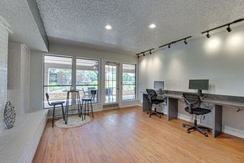 A room with a desk and chairs in front of a window.